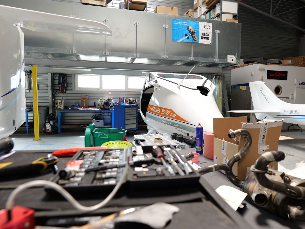 Établi de l’atelier avec outillage et pièces d’échappement, Pipistrel Virus SW 121 à l’arrière-plan