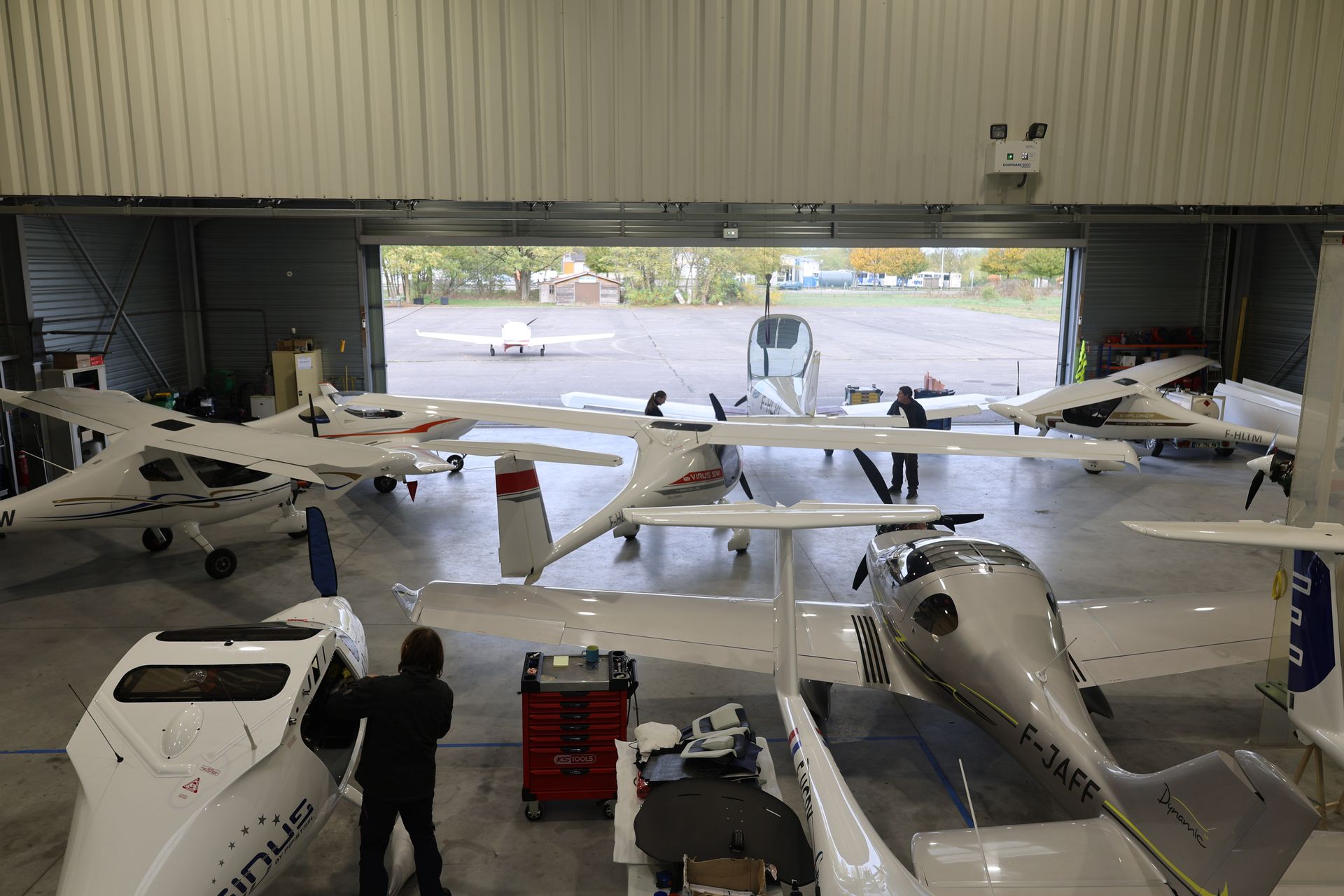 Hangar de l’atelier Finesse Max à l’aérodrome de Haguenau : ULM Pipistrel Sinus et Virus SW, Dynamic WT9 en entretien, porte ouverte sur la piste