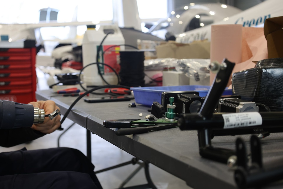 Mécanicien rétractant une gaine thermique sur un connecteur, à l’établi de l’atelier Finesse Max